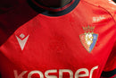 CA Osasuna 2024/2025 - Camiseta titular CA Osasuna - Macron CA Osasuna - LaLiga - Diseño clásico - Detalles modernos - Rojo - Verde - Blanco - Gola redonda - Escudo del CA Osasuna - Logo de Macron - Identidad del club - Historia del club - Tecnologías innovadoras - Confort - Rendimiento.